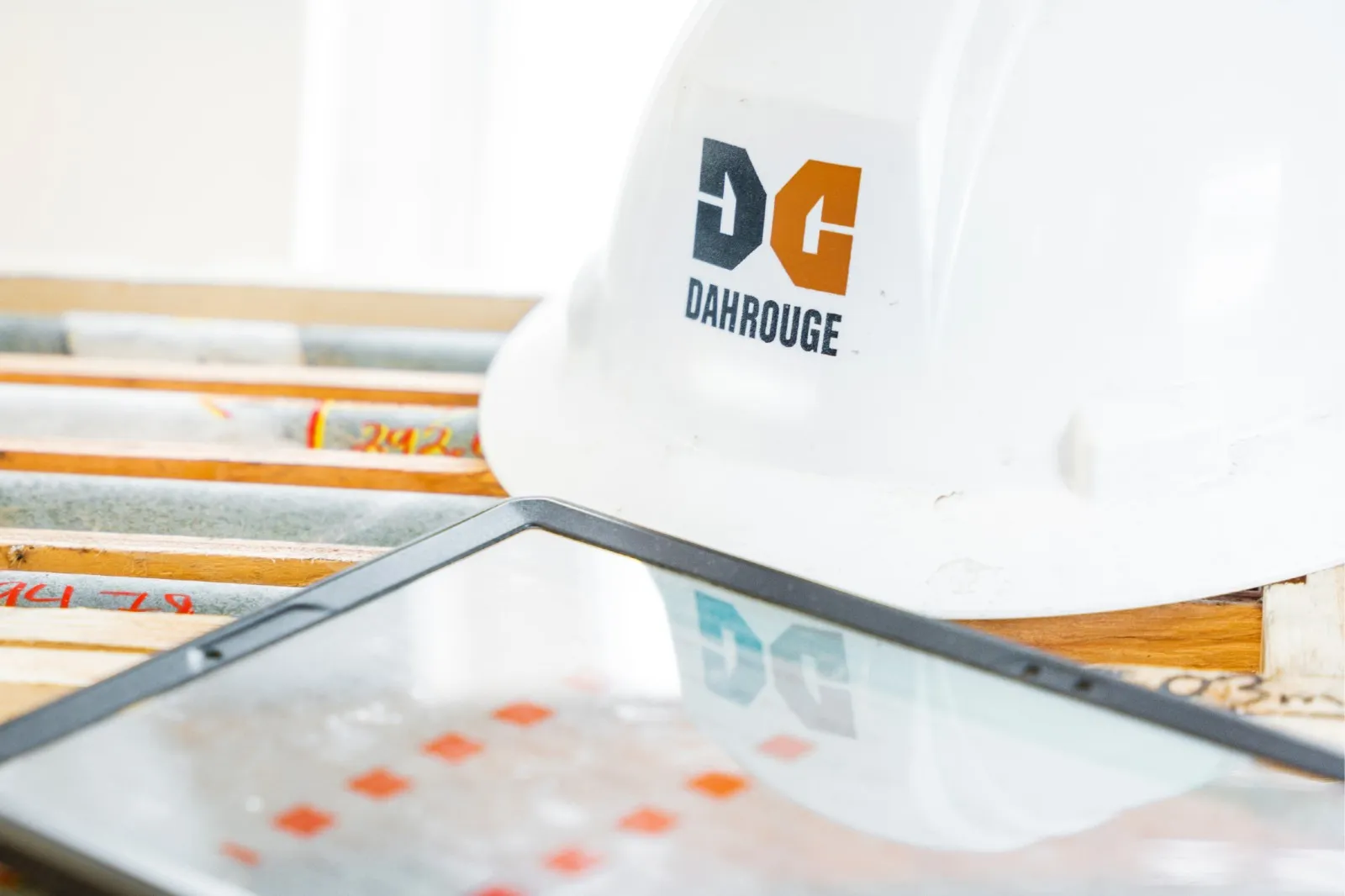 Dahrouge hard hat resting on a tablet beside drill core trays